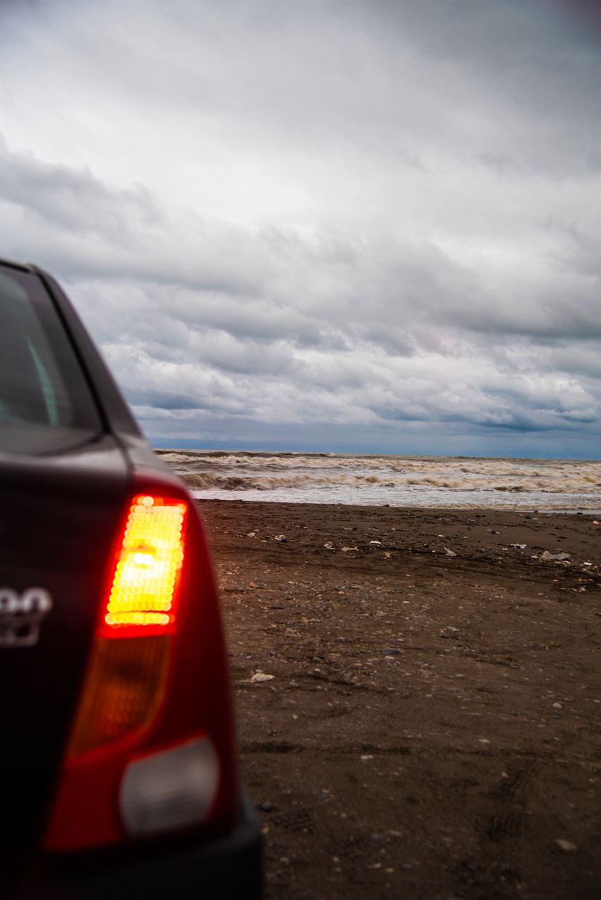 Car parked on a beach under a cloudy sky
