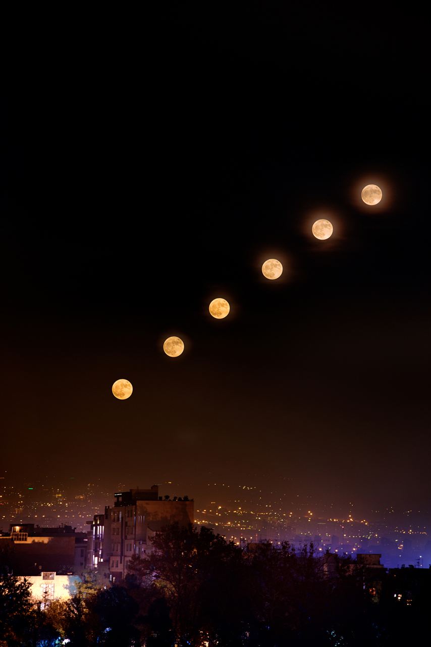 Sequence of the moon rising over a city at night